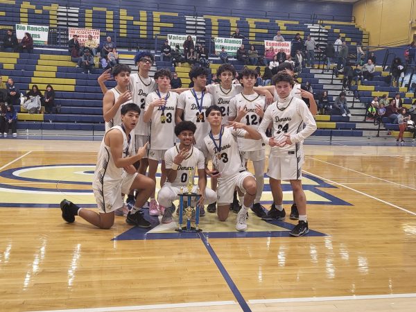 Varsity team poses with Bobby Rodriguez Capital City Tournament trophy after championship game.